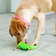 Un labrador retriever jaune avec un collier rose joue avec un jouet en peluche vert en forme de taco, cherchant des friandises cachées sur un sol carrelé.
