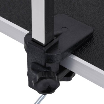 Nahaufnahme einer schwarzen Kunststoffklemme, die einen silbernen Metallpfosten an einer strukturierten schwarzen Oberfläche sichert, Teil eines Haustierpflege-Tisches.