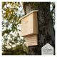 Ein Holzvogelhaus für Wildtiere, das an einem Baum montiert ist, mit einem geneigten Dach und einer Schiebetür, mit dem Logo "wildlife home" auf der Vorderseite eingraviert.
