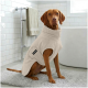 Ein beiger Hundemantel aus weichem Stoff, mit einer Klappe und einem kleinen Etikett, auf dem "THE DOG IDEA" steht.