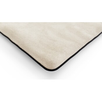 Nahaufnahme eines weichen, beigen Haustierbettes mit schwarzem Rand, das seine plüschige Textur und abgerundeten Kanten zeigt.