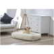Ein gemütliches Hundebett in einem modernen Wohnzimmer, mit einem hellen Hund, der darauf ruht, einem grauen Kissen auf der Couch und einer weißen Kommode in der Nähe.