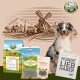 Ein glücklicher Australian Shepherd sitzt neben Bellfor Haustierfutterprodukten, mit einer Windmühle und einer "Hunde Liebhaber"-Tasche im Hintergrund.