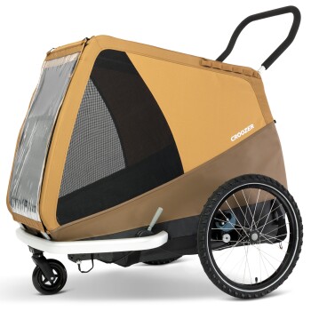 Ein brauner und tanfarbener Haustieranhänger mit einem Netzfenster, markiert mit "CROOZER", ausgestattet mit zwei Rädern und einem Griff für einfachen Transport.