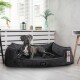 Ein grauer Hund liegt auf einem plüschigen schwarzen Hundebett in einem modernen Raum mit weißen Jalousien und dekorativen Pflanzen. Das Bett hat ein Etikett mit der Aufschrift 'tierlando'.