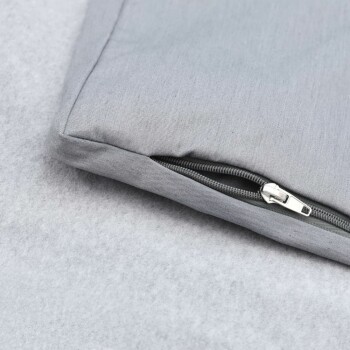 Graues Haustierbett-Eck mit einem Reißverschluss auf einer weichen, hellgrauen Oberfläche.