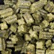 Gros plan sur des morceaux de nourriture pour animaux en forme de granulés verts, ressemblant à de petits troncs et à des croix, éparpillés sur une surface sombre.