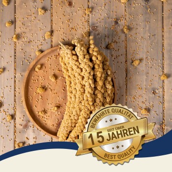 Ein Holzbrett mit geflochtenen Hirsehalmen und verstreuten Samen, mit einem "Beste Qualität" und "10 Jahre" Abzeichen.