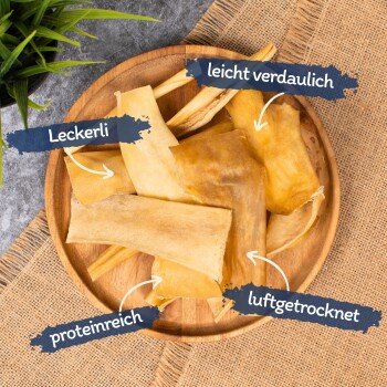 Eine Holzschüssel gefüllt mit Hundeleckerlis, beschriftet auf Deutsch: "Leckerli," "leicht verdaulich," "proteinreich," und "luftgetrocknet."