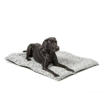 Ein schwarzer Labrador Retriever liegt auf einem weichen, grauen Haustierbett mit einer strukturierten Oberfläche.