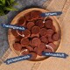 Ein Holzbrett mit runden, geschnittenen Hundetraining-Leckerlis, beschriftet auf Deutsch: "Trainingssnack," "fettarm," "gut bekömmlich," "schmackhaft."