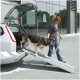 Eine Frau führt einen Hund über eine Rampe von der Rückseite eines silbernen Autos in einer modernen Außenumgebung.