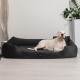 Ein großer weißer Hund liegt bequem auf einem plüschigen schwarzen Hundebett in einem modernen Raum mit einer Pflanze und einer dekorativen Lampe im Hintergrund.