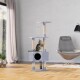 Eine graue Katze kratzt verspielt an einem mehrstöckigen Kratzbaum mit sisalüberzogenen Pfosten und einem gemütlichen Versteck, in einem modernen Wohnzimmer.