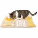 Getigert-weiße Katze schnuppert an einer beige-gelben Schnüffelmatte als Puzzlespielzeug auf weißem Hintergrund.