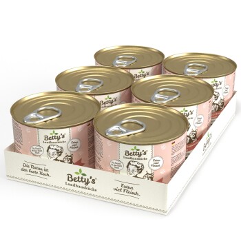 Sechs Dosen Betty's Landhausküche Tiernahrung, mit einem goldenen Deckel und pinkem Etikett, in einem Papptray präsentiert.