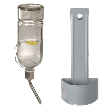 Ein klarer Glas-Wasserspender mit Messmarkierungen, der an einem Metallauslauf befestigt ist, neben einem grauen wandmontierten Halter.