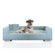 Ein gemütliches blaues Hundesofa mit zwei kleinen Kissen, auf dem ein entspannter Hund bequem liegt.