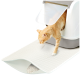 Eine hellorangefarbene getigerte Katze kommt aus einer modernen Katzentoilette auf eine strukturierte weiße Matte, die Streu auffängt.