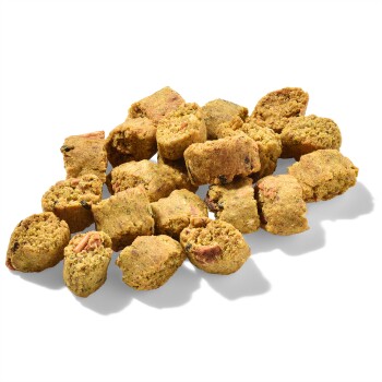 Ein Haufen kleiner, rechteckiger Haustierfutter-Kibble-Stücke in goldbrauner Farbe, verstreut auf einem transparenten Hintergrund.