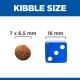 Afbeelding die de grootte van hondenbrokken vergelijkt met een blauwe dobbelsteen, met de afmetingen van de brokken gelabeld als 7 x 6,5 mm en de dobbelsteenmaat als 16 mm.