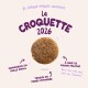 Croquette ronde brun unique avec texte violet «La Croquette 2026» et notes en français : viande fraîche, petite taille, fibres optimisées.