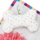 Un jouet en peluche doux et blanc en forme d'os, décoré de pois colorés, placé sur un fond à motifs vibrants.