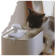 Eine schwarz-weiße Katze trinkt aus einem modernen Haustier-Wasserbrunnen mit fließendem Wasser, auf einer Holzoberfläche platziert.