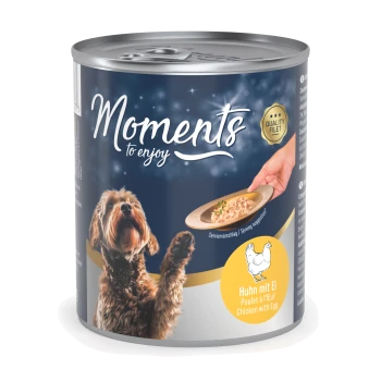 Eine Dose Hundefutter mit der Aufschrift "Moments to enjoy", die einen braunen Hund zeigt, der auf einen Teller mit Futter schaut. Der Text lautet "Huhn mit Ei".