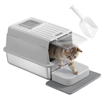 Graue Katzenstreu-Box mit Deckel, eine Katze steigt heraus, eine Schaufel und eine graue Matte darunter auf weißem Hintergrund.