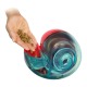 Hand schüttet Trockenfutter in ein türkisfarbenes Spiral-Leckerli-Spielzeug mit rotem Inneren (Text 'KONG' sichtbar).