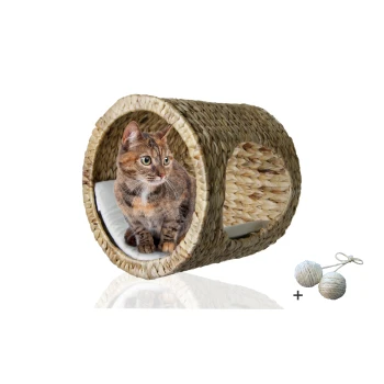 ® Katzenhöhle für Wandmontage, Kletterwand-Element mit Gratis-Spielballset Eine getigerte Katze sitzt in einem runden, geflochtenen Strohkatzenschlafplatz mit einem weichen Kissen, begleitet von zwei kleinen, runden Katzenspielzeugen.