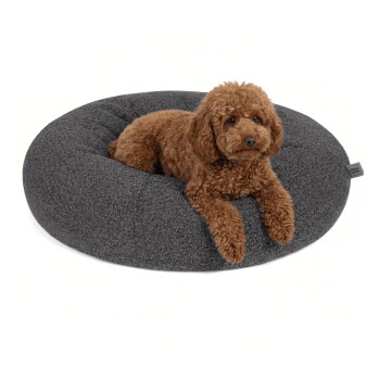 Runde, plüschige Hundebett aus dunkelgrauem Stoff mit einem gepolsterten Design, mit einem kleinen Anhänger, auf dem 'RAW' steht.