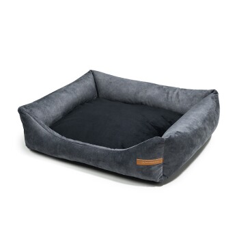 Graues Haustierbett mit einer plüschigen, weichen Oberfläche und erhöhten Rändern, mit einem kleinen Lederetikett an der Seite.