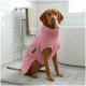 Ein weicher rosa Hundemantel mit einem runden Kragen und einem Riemen mit zwei Metallschnappverschlüssen, beschriftet mit "THE DOG IDEA."