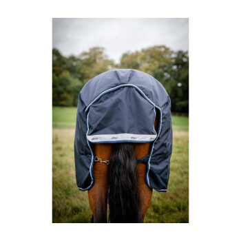 Ein Pferd trägt eine marineblaue Decke mit hellblauen Akzenten, zeigt die Rückansicht und seinen langen Schwanz, vor einem grasbewachsenen Feld.