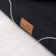Eine Nahaufnahme eines schwarzen Haustierbettes mit einem hellbraunen Lederschild mit dem Markennamen "tierlando" auf einem hellen Holzboden.