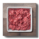 Ein quadratisches weißes Geschirr, gefüllt mit rohem Hackfleisch, auf einer Holzoberfläche platziert.