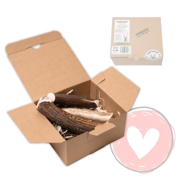 Geöffnete Kraftpapierbox mit Rehgeweih-Kauartikeln für Hunde, darüber eine kleine geschlossene FOURLEGS-gebrandete Schachtel und ein rosafarbenes Herz unten rechts.