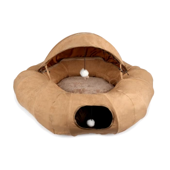 Beiges rundes Plüschhaustierbett mit Baldachin, Tunneleingang und zwei hängenden weißen Bommel-Spielzeugen, weich gepolsterte Innenseite