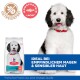 Ein flauschiger schwarz-weißer Hund sitzt neben einem Sack Hill's Science Plan Hundefutter, beschriftet mit "Hypoallergen" und "Ideal für empfindliche Mägen & Haut."