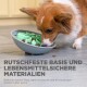 Ein Hund frisst aus einer grauen Schüssel mit grünen, lebensmittelechten Einsätzen, mit einem Text über die rutschfeste Basis und sichere Materialien.