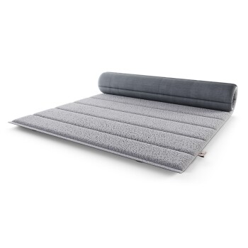 Graues Haustierbett mit einer plüschigen, strukturierten Oberfläche und einem zylindrischen Bolsterkissen an einem Ende, entworfen für Komfort und Unterstützung.