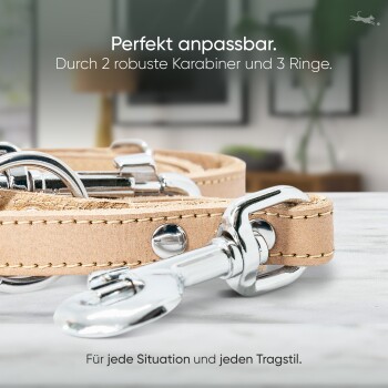 Nahaufnahme einer Hundeleine mit zwei Metallclips und drei Ringen, mit Text über ihre Anpassungsfähigkeit für verschiedene Situationen.
