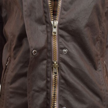 Nahaufnahme einer braunen Jacke mit Messingreißverschluss und Druckknöpfen, zeigt ein kariertes Innenfutter.