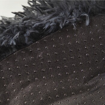 Nahaufnahme einer plüschigen schwarzen Haustierdecke mit weichen, flauschigen Rändern und einem strukturierten, gepunkteten Stoffuntergrund.