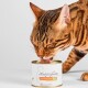 Braun-getigerte Katze leckt an einer Dose Katzenfutter mit der Aufschrift 'Katzenfutter', '95% Fleischanteil', 'Huhn'; Marke 'Lucky-kitty'.