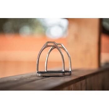 Zwei glänzende Metallsteigbügel mit Gummistreifen, beschriftet mit "EQUINATE", die auf einer Holzoberfläche mit verschwommenem Hintergrund ruhen.