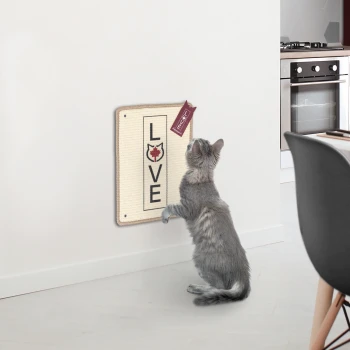 Eine verspielte graue Katze, die nach einem wandmontierten Kratzbrett greift, auf dem 'LOVE' steht, mit einem kleinen Anhänger.