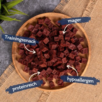 Eine Holzschüssel mit würfelförmigen Hundeleckerlis, die als fettarm, proteinreich und hypoallergen gekennzeichnet sind.